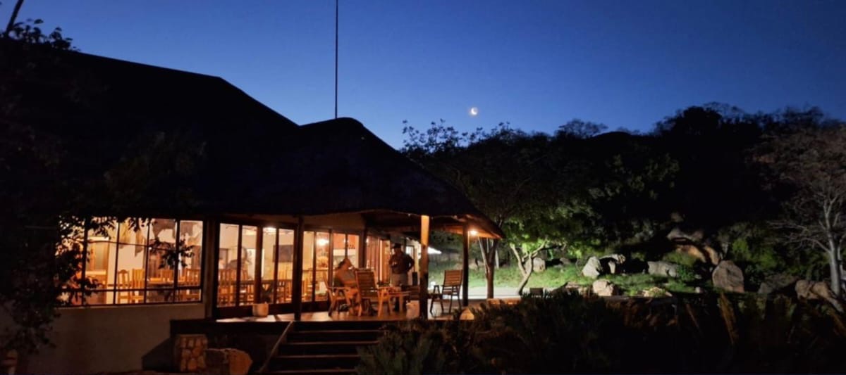 The main lodge lit up at dusk beneath a crescent moon